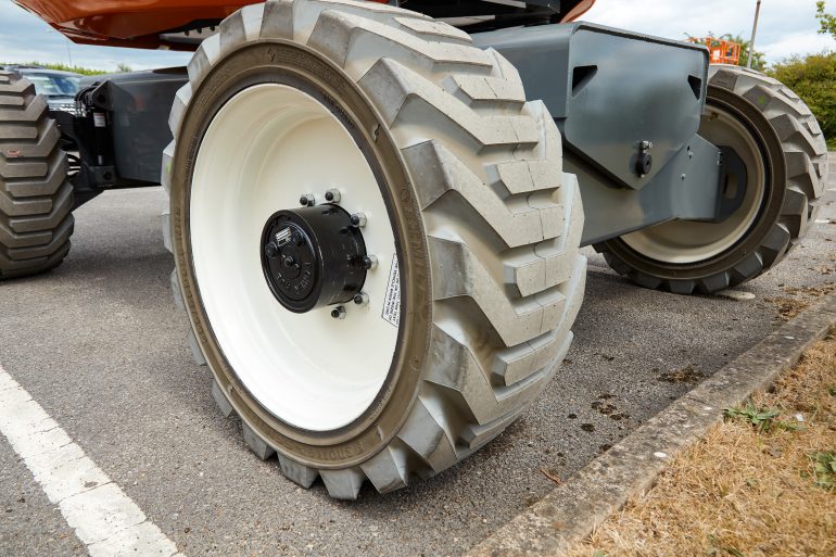 The wheels and raised chassis of a rough terrain cherry picker.