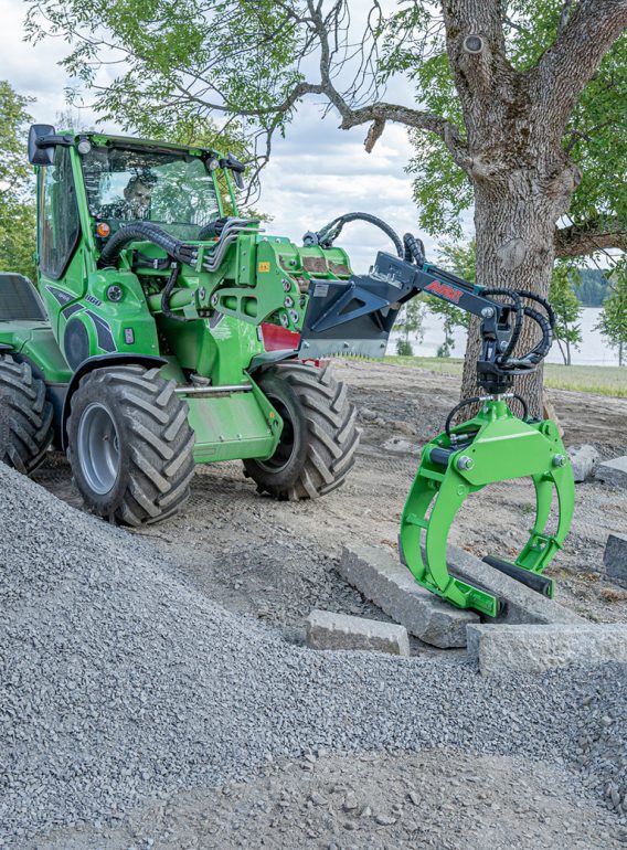 A compact loader with a curb stone lifter attachmment.