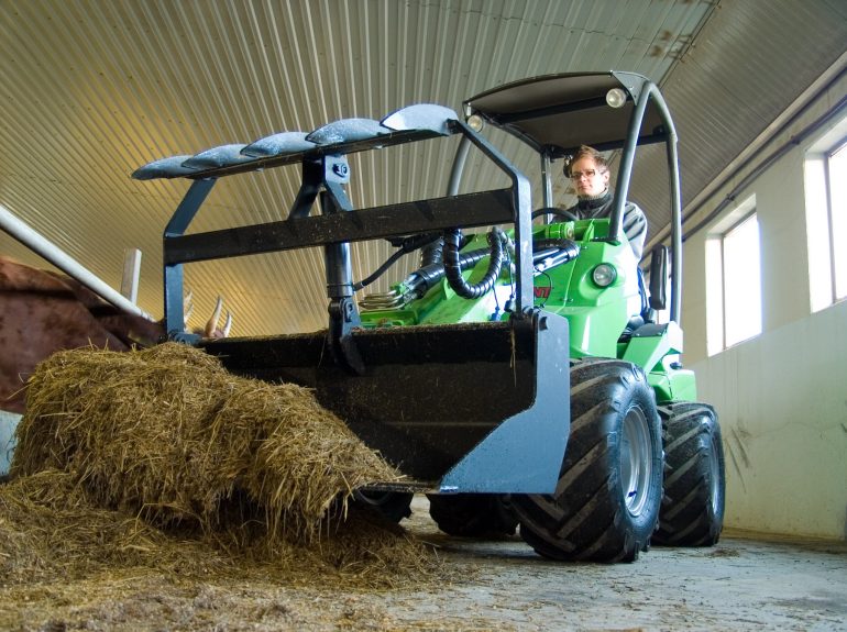 A compact loader with a grapple bucket.